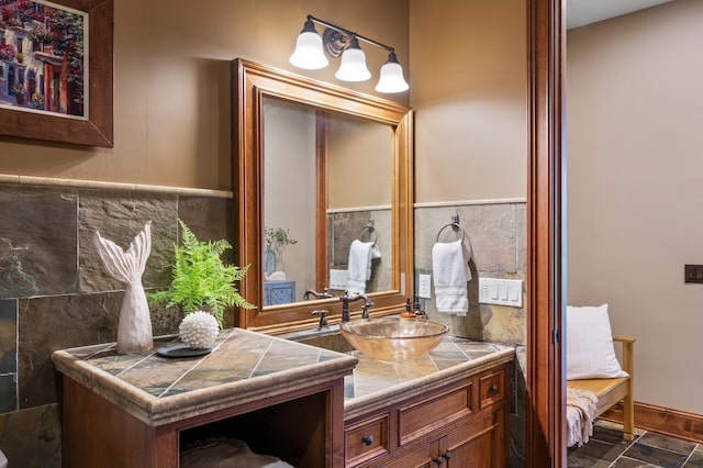 bathroom with tile walls, vanity, and stone finish flooring
