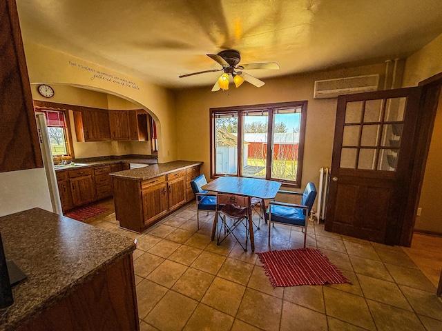 dining space with arched walkways, plenty of natural light, tile patterned flooring, and ceiling fan