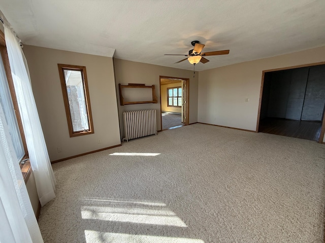 interior space featuring a ceiling fan, baseboards, and radiator heating unit