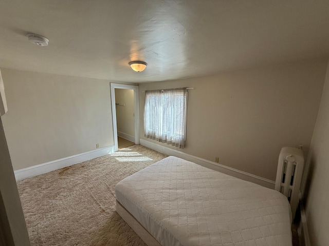 bedroom with radiator, light carpet, and baseboards