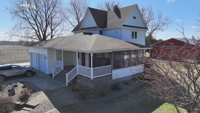 view of front of house with a chimney, concrete driveway, a porch, roof with shingles, and a garage