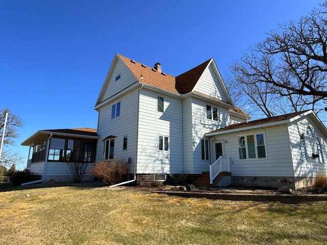 view of side of property with a lawn, a shingled roof, and a sunroom