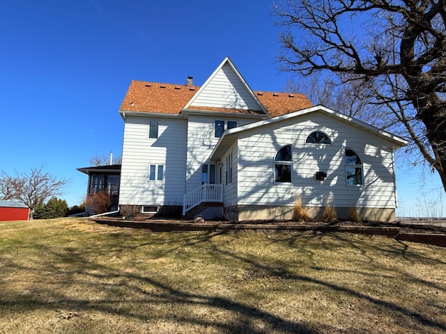 rear view of house with a yard and a shingled roof