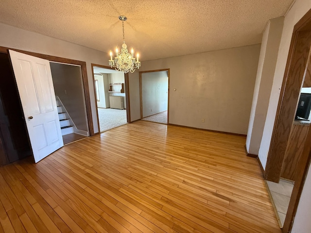 20343 680th Ave, Alden, MN 56009 - unfurnished dining area featuring a chandelier, light wood-style floors, a textured ceiling, and stairs