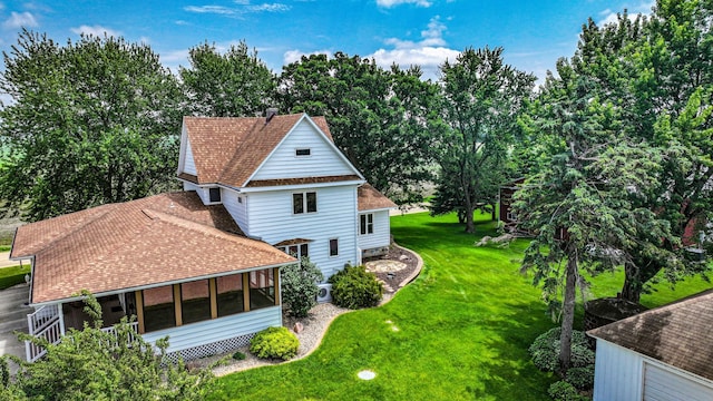 20343 680th Ave, Alden, MN 56009 - view of home's exterior featuring a sunroom, a chimney, a shingled roof, a lawn, and view of scattered trees