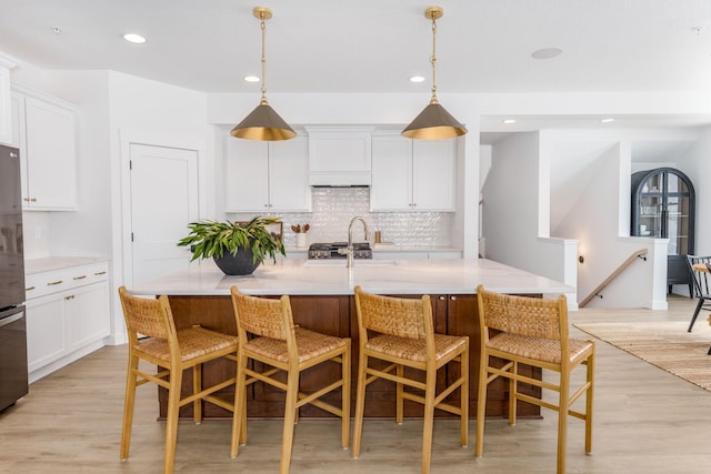 kitchen featuring decorative backsplash, a breakfast bar, recessed lighting, and white cabinets