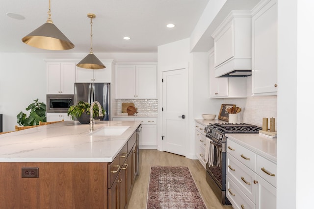 kitchen featuring a sink, stainless steel appliances, recessed lighting, white cabinetry, and a center island with sink