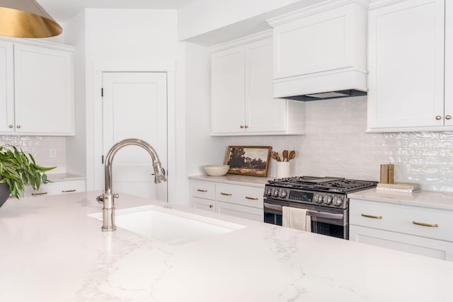 kitchen featuring a sink, white cabinets, stainless steel gas range oven, and tasteful backsplash