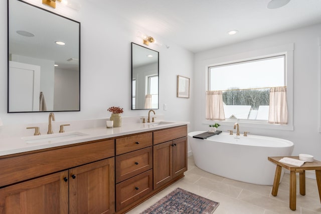bathroom with a sink, a freestanding tub, tile patterned flooring, and double vanity