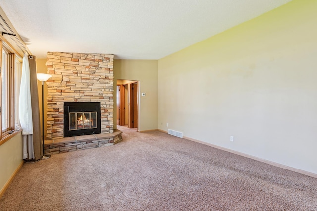 unfurnished living room featuring carpet, a stone fireplace, and baseboards