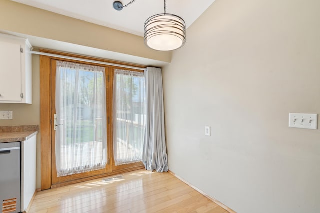 unfurnished dining area with light wood-style floors and baseboards