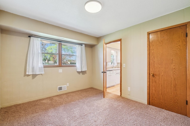 unfurnished bedroom featuring light colored carpet, a sink, and baseboards