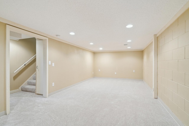 finished basement with recessed lighting, light carpet, stairs, baseboards, and crown molding
