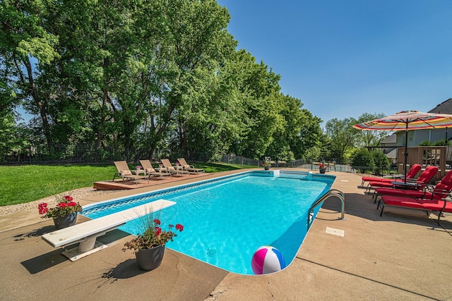 view of pool featuring a diving board, a patio area, and view of scattered trees