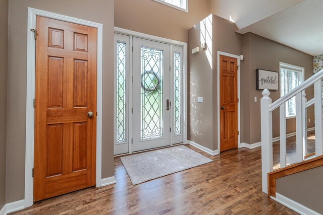 foyer entrance with wood finished floors, baseboards, and stairway