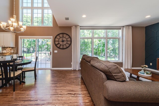 living room featuring baseboards, a chandelier, wood finished floors, recessed lighting, and a towering ceiling