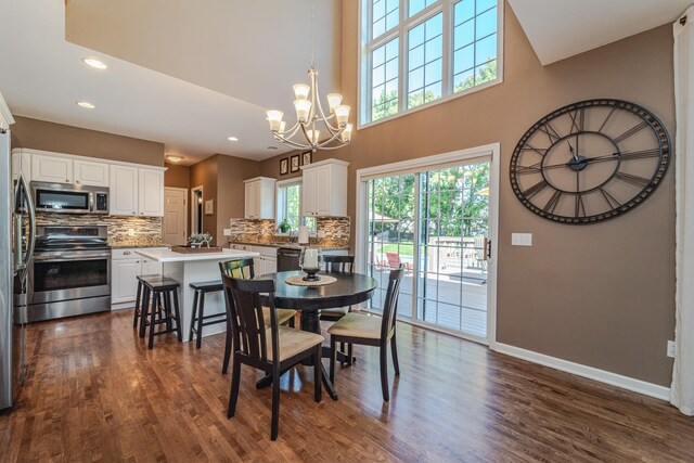 dining space with a chandelier, baseboards, dark wood-style floors, recessed lighting, and a high ceiling