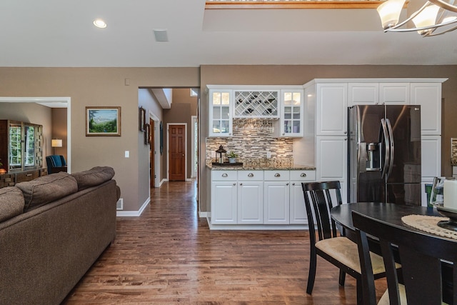 kitchen featuring stainless steel refrigerator with ice dispenser, dark wood-type flooring, backsplash, a chandelier, and glass insert cabinets