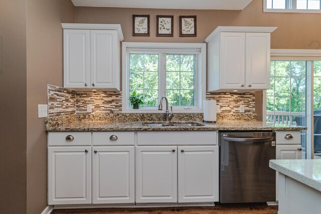 kitchen featuring stainless steel dishwasher, a sink, decorative backsplash, and white cabinets