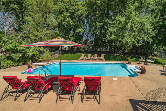 outdoor pool featuring fence, a patio area, and view of wooded area