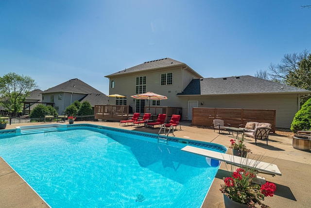 view of swimming pool with a diving board, a patio area, a deck, and fence