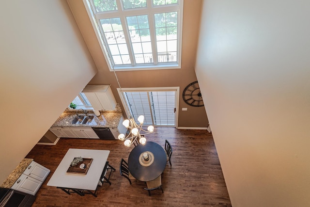 living area featuring dark wood-type flooring, baseboards, a chandelier, and a high ceiling
