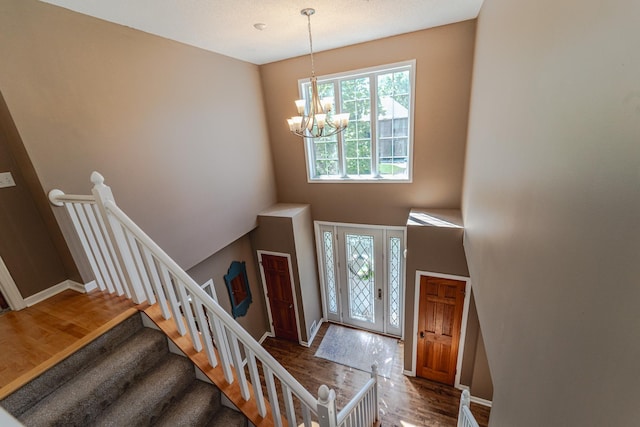 foyer entrance with a chandelier, wood finished floors, baseboards, and a high ceiling