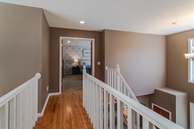 hall featuring an upstairs landing, light wood-style floors, and recessed lighting