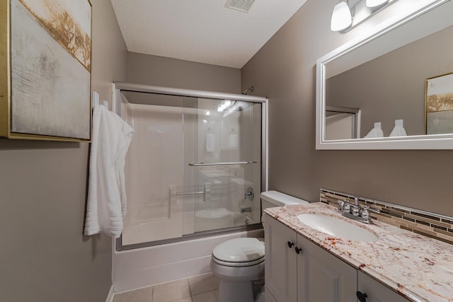 bathroom featuring toilet, vanity, tile patterned floors, and shower / bath combination with glass door