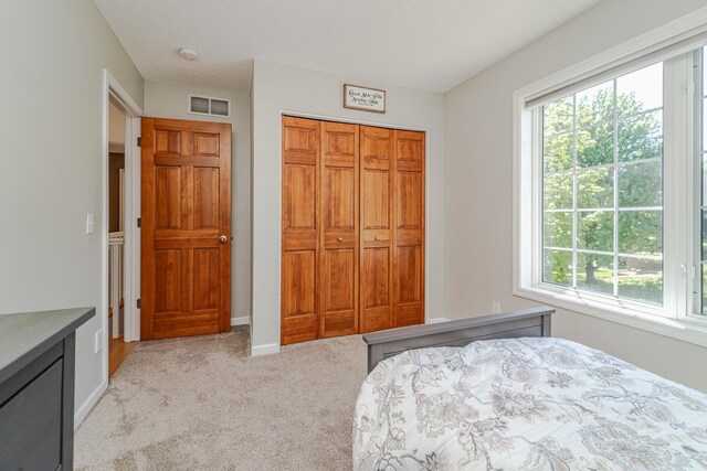 bedroom with light carpet, a closet, and baseboards