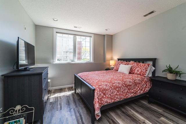 bedroom featuring dark wood-type flooring, a textured ceiling, and baseboards