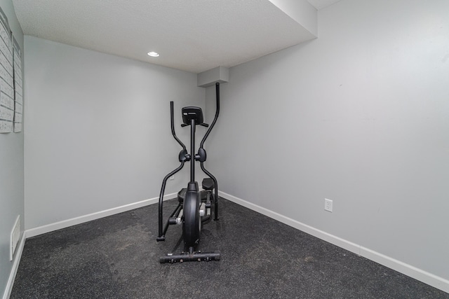 exercise area featuring baseboards, recessed lighting, and a textured ceiling
