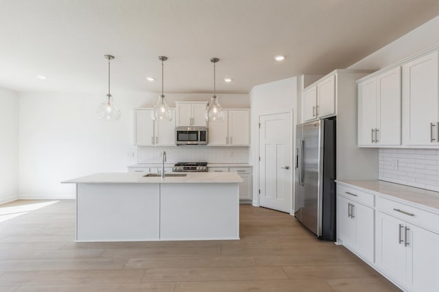 kitchen featuring a sink, decorative backsplash, appliances with stainless steel finishes, and white cabinetry