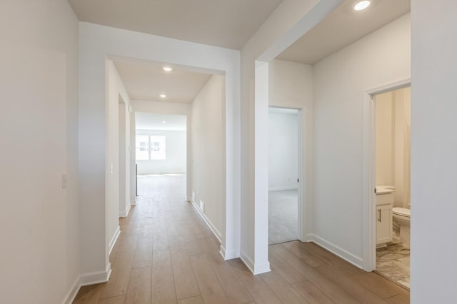 hall with recessed lighting, light wood finished floors, and baseboards