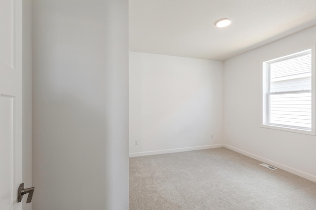 empty room featuring light colored carpet, baseboards, and visible vents