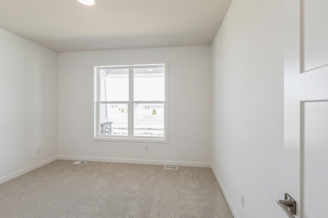 spare room featuring visible vents, baseboards, and light colored carpet