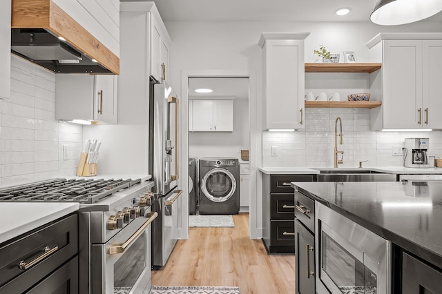 kitchen featuring a sink, wall chimney range hood, white cabinets, and premium appliances