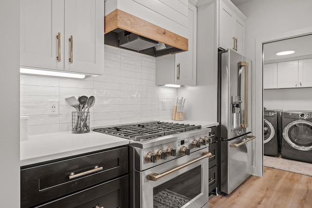 kitchen with premium appliances, washer and dryer, white cabinets, and custom range hood