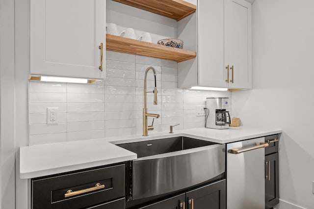 kitchen featuring tasteful backsplash, light countertops, open shelves, and a sink