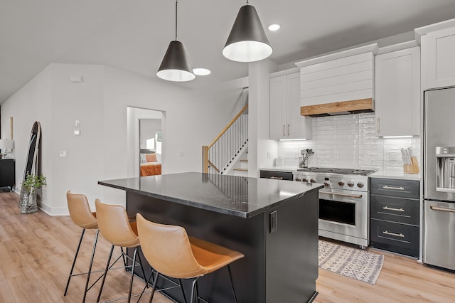 kitchen featuring light wood-type flooring, a center island, a kitchen bar, decorative backsplash, and stainless steel appliances