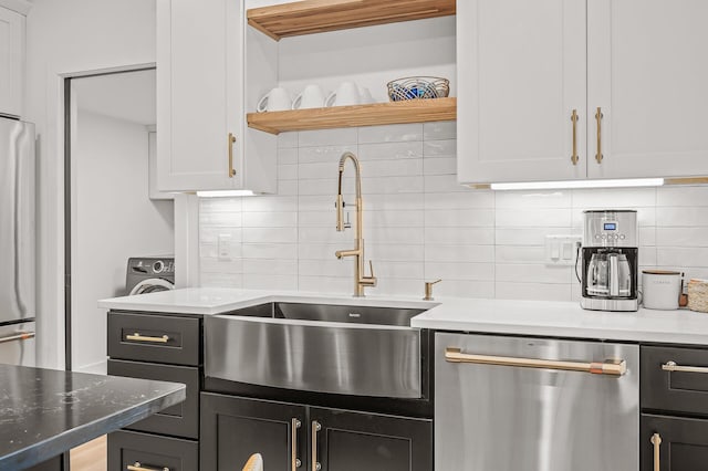 kitchen with tasteful backsplash, white cabinetry, appliances with stainless steel finishes, light stone counters, and a sink
