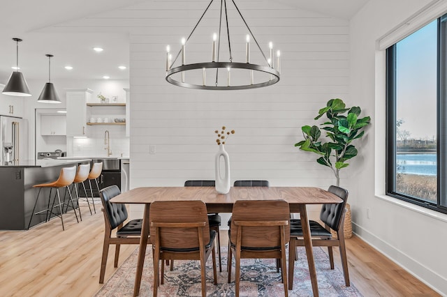 dining area with a chandelier, light wood-style floors, lofted ceiling, and plenty of natural light