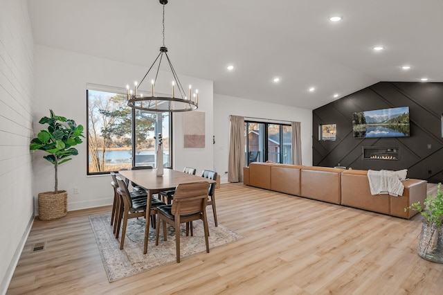 dining space featuring light wood-type flooring, visible vents, a chandelier, lofted ceiling, and baseboards