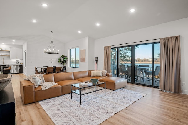 living area with light wood-type flooring, an inviting chandelier, vaulted ceiling, and recessed lighting