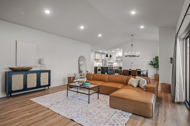 living area with a chandelier, light wood finished floors, lofted ceiling, and recessed lighting