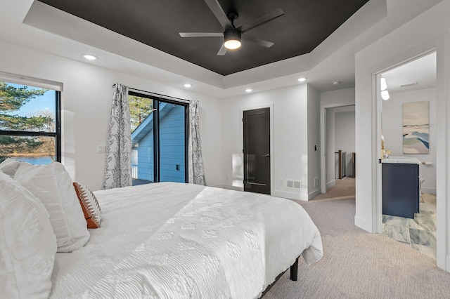 bedroom with visible vents, a raised ceiling, light colored carpet, and recessed lighting
