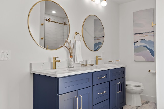 bathroom with toilet, double vanity, a sink, and baseboards
