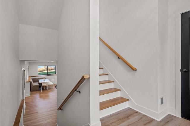 staircase featuring wood finished floors and a high ceiling