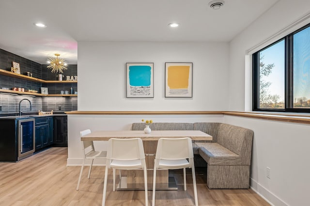 dining area with indoor wet bar, baseboards, recessed lighting, light wood-style flooring, and wine cooler