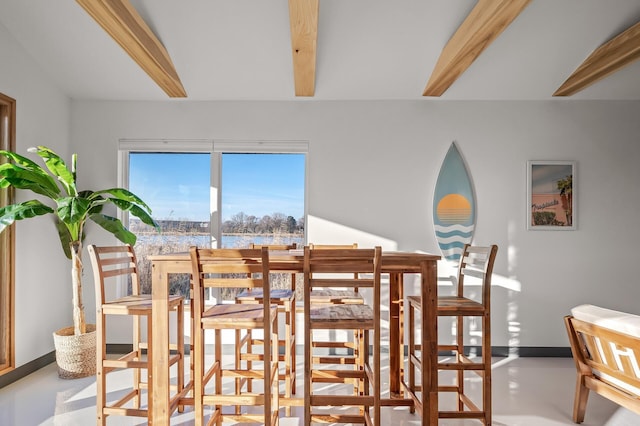 dining room with baseboards, concrete flooring, and beam ceiling